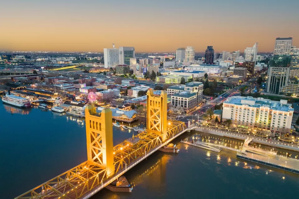 View of Tower Bridge over Sacramento River and downtown Sacramento, California at dusk.